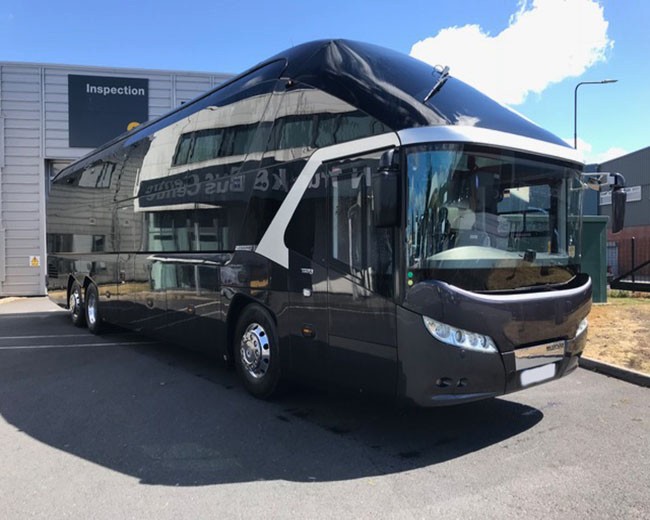 A sleek 50-seater coach parked near a scenic view